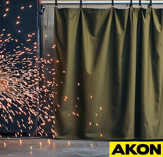 Roll-up retractable welding screens with heavy-duty curtains on portable frame, designed to protect work areas from sparks and UV light in fabrication environments