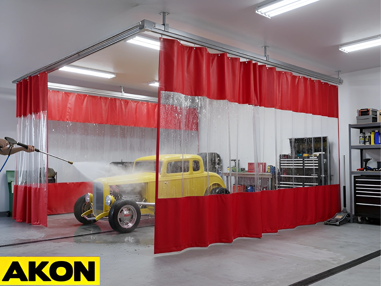 AKON red garage wash bay curtains forming a vehicle wash enclosure while a classic car is pressure washed inside a garage