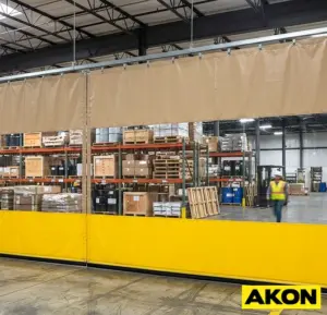 Industrial protective divider curtains hanging in a large facility to separate work zones.