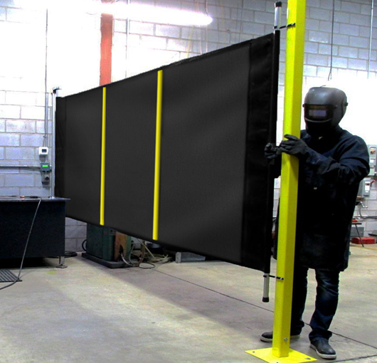Opaque industrial safety curtain installed on a freestanding frame, providing protection from sparks, light, and debris during welding or grinding operations.