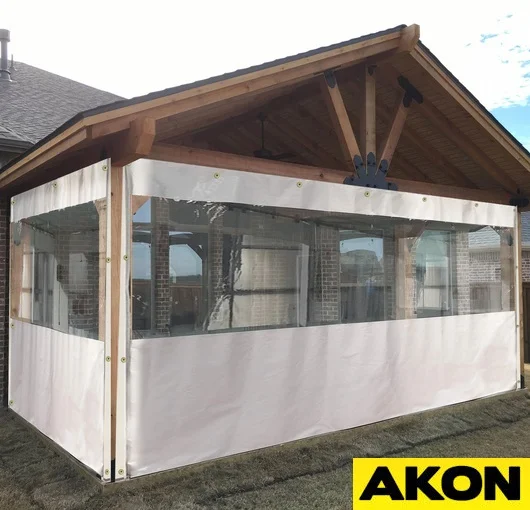 White outdoor weather wall curtains with integrated clear window panels enclosing a wooden gazebo for privacy and seasonal protection.