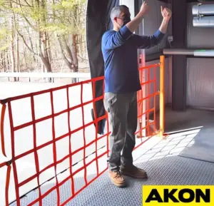 Orange safety fall netting installed at a loading dock edge to prevent workers from falling.