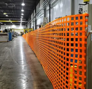 Warehouse barrier netting installed in an industrial facility to separate work zones or restrict access to storage areas.